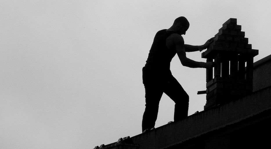 Professioneller Schornsteinfeger, der einen Schornstein reinigt